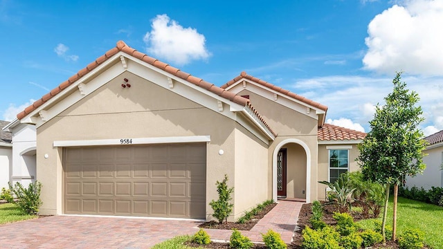 9584 SW Royal Poinciana Dr, Port Saint Lucie, FL 34987 - mediterranean / spanish house featuring a garage, a tiled roof, decorative driveway, and stucco siding