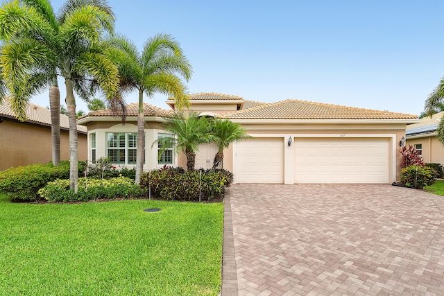 8271 Green Mountain Rd, Boynton Beach, FL 33473 - mediterranean / spanish house with decorative driveway, a front lawn, stucco siding, and an attached garage