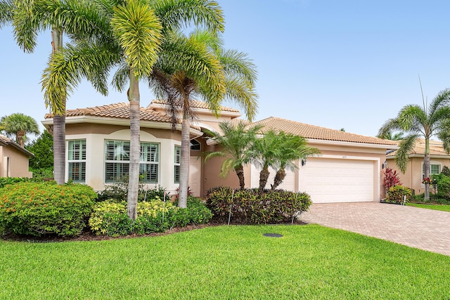 8271 Green Mountain Rd, Boynton Beach, FL 33473 - mediterranean / spanish-style home with decorative driveway, a garage, a front yard, stucco siding, and a tiled roof