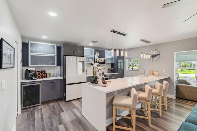 1170 S Drive Cir Unit B, Delray Beach, FL 33445 - kitchen with freestanding refrigerator, beverage cooler, a breakfast bar, a peninsula, and wood finished floors