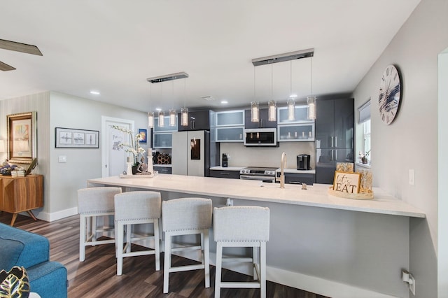 1170 S Drive Cir Unit B, Delray Beach, FL 33445 - kitchen with white appliances, a kitchen breakfast bar, light countertops, dark wood finished floors, and a peninsula