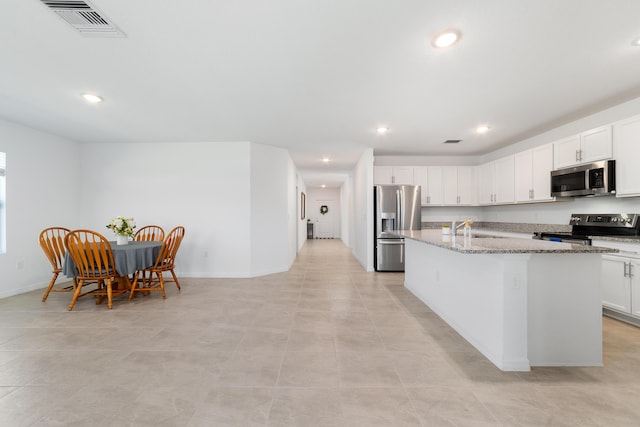 1312 SW Calmar Ave Unit 164, Port Saint Lucie, FL 34953 - kitchen with appliances with stainless steel finishes, an island with sink, light stone countertops, white cabinets, and recessed lighting