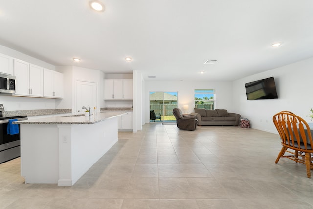 1312 SW Calmar Ave Unit 164, Port Saint Lucie, FL 34953 - kitchen featuring appliances with stainless steel finishes, white cabinetry, open floor plan, light stone counters, and a center island with sink