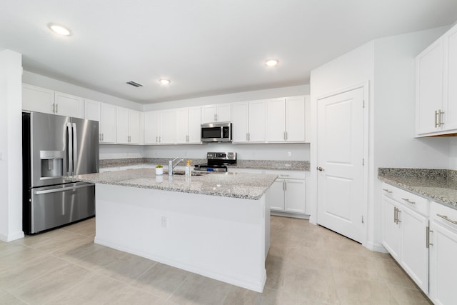 1312 SW Calmar Ave Unit 164, Port Saint Lucie, FL 34953 - kitchen with appliances with stainless steel finishes, white cabinetry, light stone counters, an island with sink, and recessed lighting