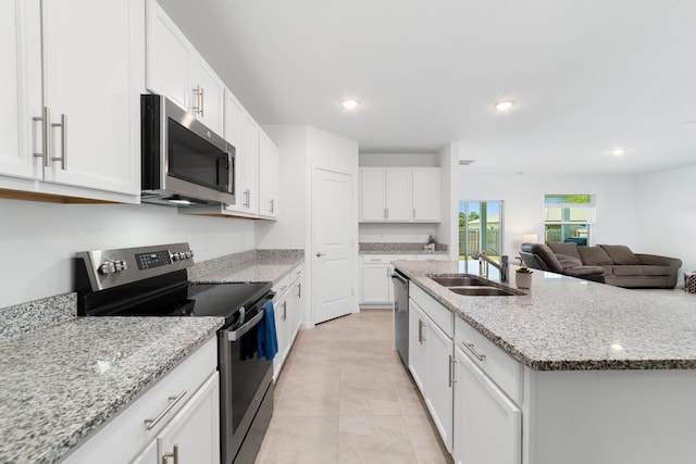 1312 SW Calmar Ave Unit 164, Port Saint Lucie, FL 34953 - kitchen featuring appliances with stainless steel finishes, white cabinets, an island with sink, light tile patterned flooring, and light stone countertops