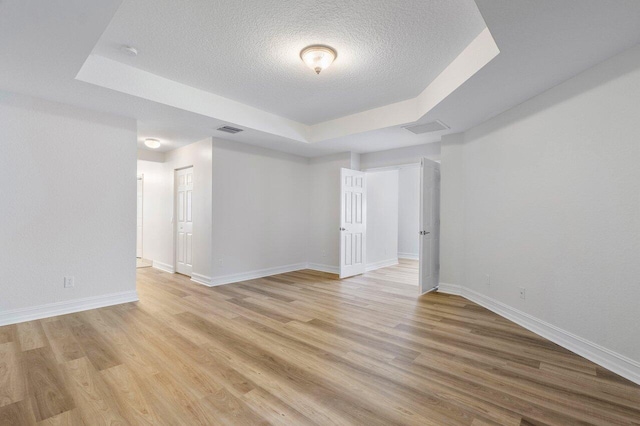 8183 Emerald Winds Cir, Boynton Beach, FL 33473 - unfurnished room with a tray ceiling, a textured ceiling, and light wood-style floors