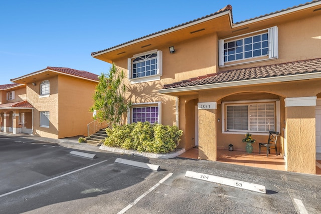 7853 W 36th Ave Unit 104, Hialeah, FL 33018 - multi unit property with a tiled roof, stucco siding, and uncovered parking