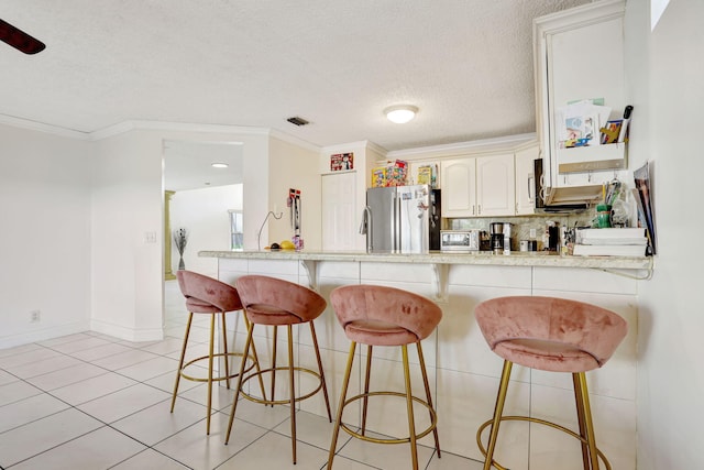 3385 Seabreeze Ln, Margate, FL 33063 - kitchen with freestanding refrigerator, a breakfast bar, a textured ceiling, crown molding, and light countertops