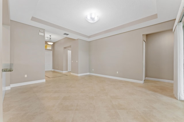 2854 Bellarosa Cir, Royal Palm Beach, FL 33411 - empty room featuring a tray ceiling, light tile patterned floors, and a textured ceiling