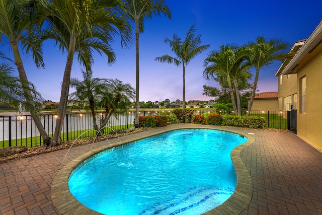 2854 Bellarosa Cir, Royal Palm Beach, FL 33411 - pool at dusk featuring a water view, a fenced backyard, and a patio area