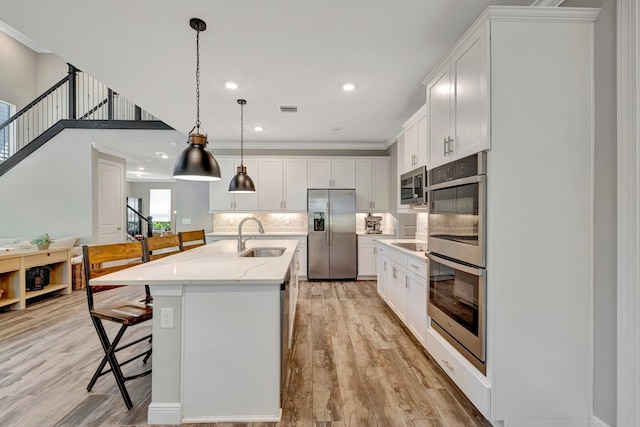 4610 SW Ardsley Dr, Stuart, FL 34997 - kitchen with stainless steel appliances, a breakfast bar, white cabinetry, decorative backsplash, and light wood finished floors