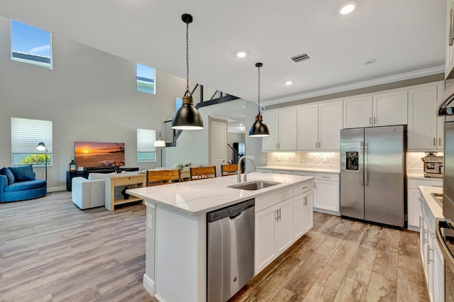 4610 SW Ardsley Dr, Stuart, FL 34997 - kitchen featuring appliances with stainless steel finishes, an island with sink, light wood-style flooring, decorative backsplash, and recessed lighting