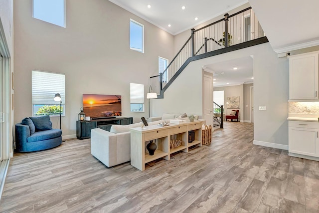 4610 SW Ardsley Dr, Stuart, FL 34997 - living room featuring a high ceiling, ornamental molding, stairway, light wood-type flooring, and healthy amount of natural light