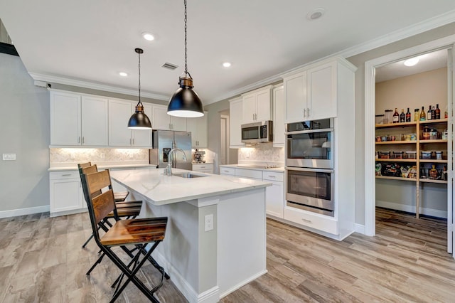 4610 SW Ardsley Dr, Stuart, FL 34997 - kitchen featuring appliances with stainless steel finishes, ornamental molding, tasteful backsplash, an island with sink, and white cabinetry