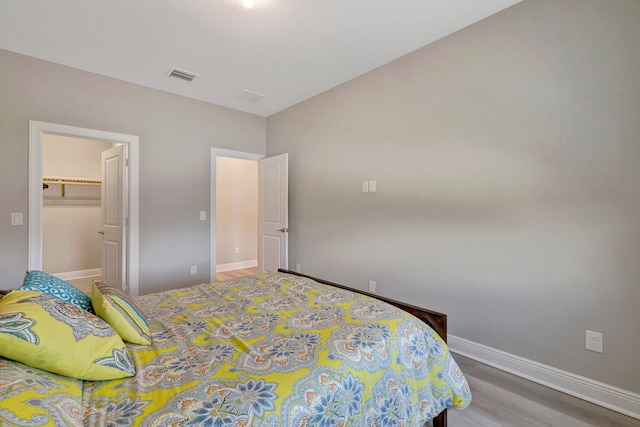 4610 SW Ardsley Dr, Stuart, FL 34997 - bedroom featuring a walk in closet, wood finished floors, and a closet