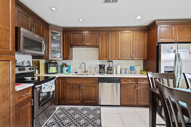 5800 Fernley Dr W Unit 54, West Palm Beach, FL 33415 - kitchen featuring appliances with stainless steel finishes, light countertops, tasteful backsplash, light tile patterned floors, and glass insert cabinets