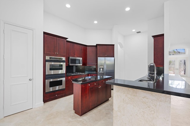 16284 Via Venetia W, Delray Beach, FL 33484 - kitchen featuring reddish brown cabinets, appliances with stainless steel finishes, dark countertops, a kitchen island, and recessed lighting