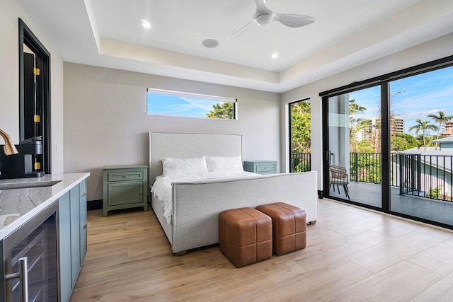 13480 US Highway 1, Juno Beach, FL 33408 - bedroom with access to exterior, beverage cooler, a tray ceiling, light wood-style flooring, and ceiling fan