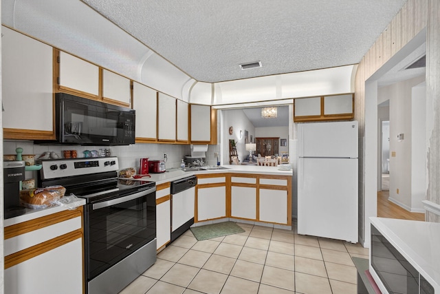 2640 Gately Dr W Unit 1604, West Palm Beach, FL 33415 - kitchen featuring white appliances, light countertops, a textured ceiling, light tile patterned floors, and white cabinetry