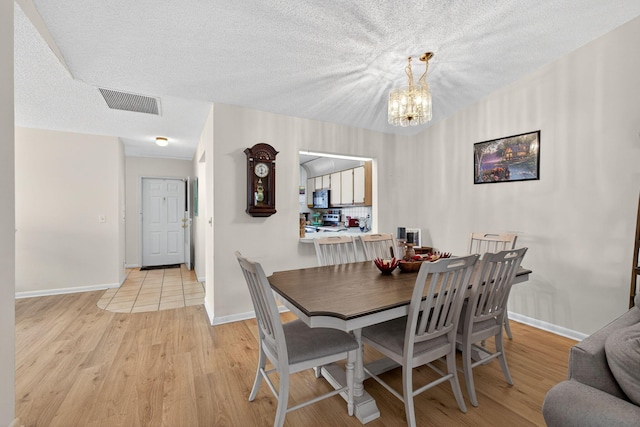 2640 Gately Dr W Unit 1604, West Palm Beach, FL 33415 - dining room with a chandelier, light wood-style floors, and a textured ceiling