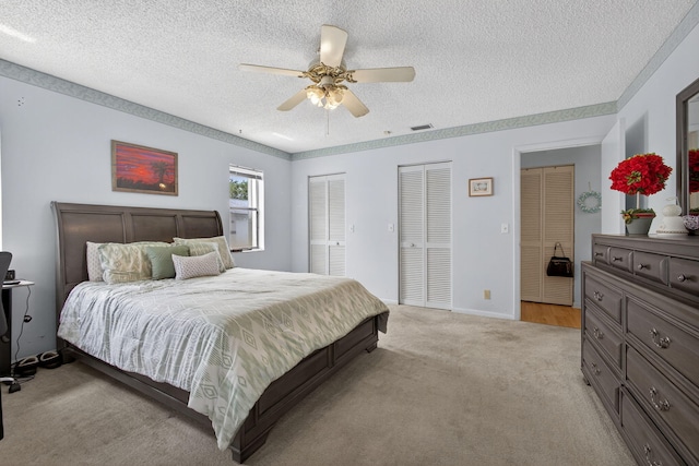 2640 Gately Dr W Unit 1604, West Palm Beach, FL 33415 - bedroom with multiple closets, a textured ceiling, light carpet, and a ceiling fan