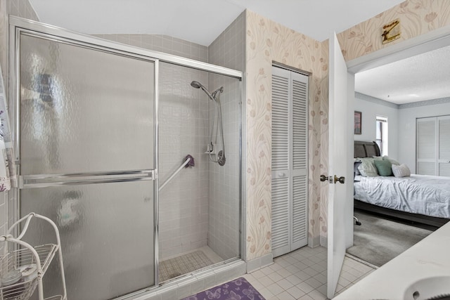 2640 Gately Dr W Unit 1604, West Palm Beach, FL 33415 - ensuite bathroom featuring wallpapered walls, a shower stall, a closet, tile patterned floors, and vaulted ceiling