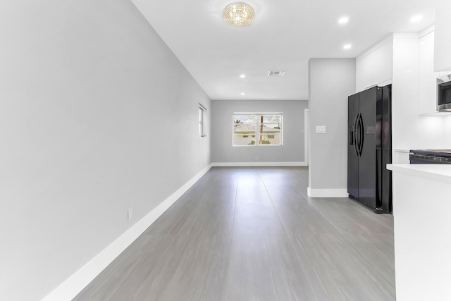 7609 NW 70th Ave, Tamarac, FL 33321 - kitchen with black fridge, white cabinets, light countertops, light wood-style floors, and modern cabinets