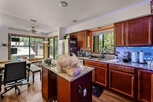 5310 Pebble Beach Dr Unit F, Orlando, FL 32811 - kitchen with freestanding refrigerator, wood finished floors, light stone countertops, ceiling fan, and a textured ceiling