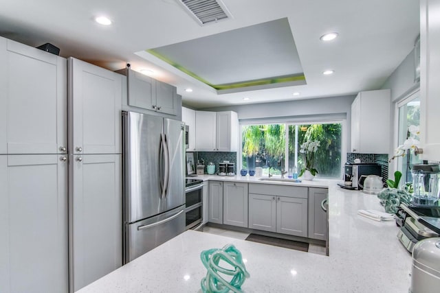 8 Wellesley Dr, Lake Worth Beach, FL 33460 - kitchen featuring stainless steel appliances, decorative backsplash, light stone counters, recessed lighting, and gray cabinetry