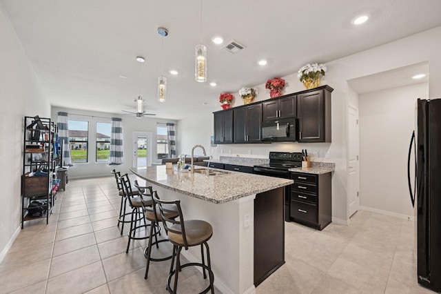 2808 Troubadour St, Palm Springs, FL 33406 - kitchen featuring black appliances, a breakfast bar area, recessed lighting, light stone countertops, and light tile patterned floors