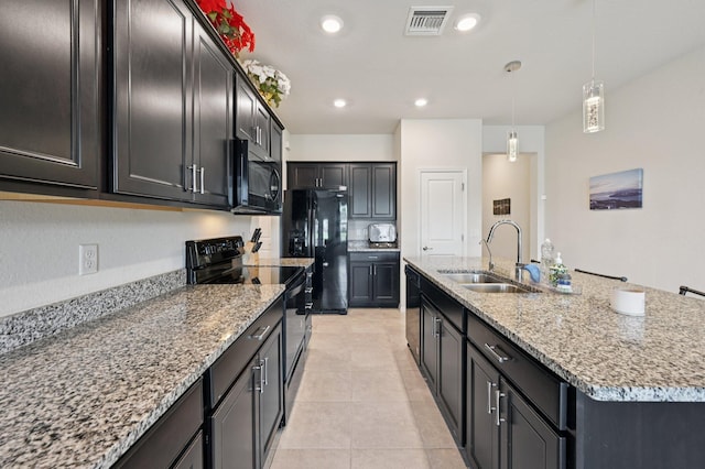 2808 Troubadour St, Palm Springs, FL 33406 - kitchen featuring black appliances, light stone counters, a center island with sink, hanging light fixtures, and light tile patterned floors