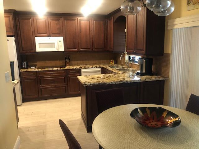 7992 Chula Vista Cres, Boca Raton, FL 33433 - kitchen with white appliances, backsplash, light stone countertops, and light wood-style flooring