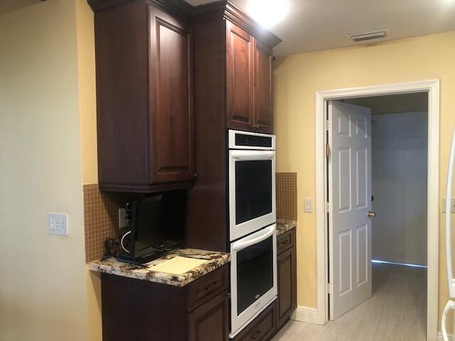 7992 Chula Vista Cres, Boca Raton, FL 33433 - kitchen featuring double oven, light stone countertops, and dark brown cabinets