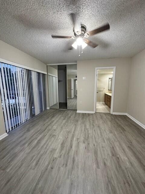3310 33rd Way, West Palm Beach, FL 33407 - unfurnished bedroom featuring wood finished floors, a textured ceiling, ceiling fan, and ensuite bath