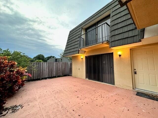 3310 33rd Way, West Palm Beach, FL 33407 - entrance to property featuring stucco siding, mansard roof, a balcony, and a patio