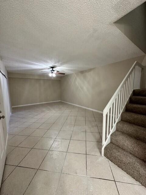 3310 33rd Way, West Palm Beach, FL 33407 - empty room with light tile patterned floors, ceiling fan, stairs, and a textured ceiling