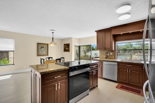 6526 Sweet Maple Ln, Boca Raton, FL 33433 - kitchen featuring appliances with stainless steel finishes, a textured ceiling, a kitchen island, dark stone countertops, and decorative backsplash
