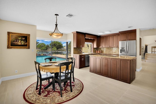 6526 Sweet Maple Ln, Boca Raton, FL 33433 - kitchen featuring appliances with stainless steel finishes, backsplash, a kitchen island, decorative light fixtures, and light stone countertops