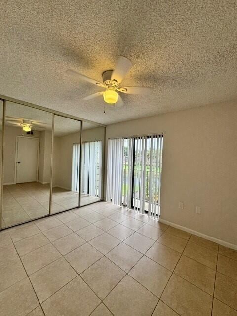 3822 38th Way, West Palm Beach, FL 33407 - unfurnished bedroom with light tile patterned flooring, a textured ceiling, a closet, and a ceiling fan