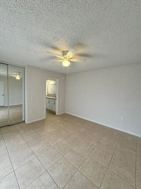 3822 38th Way, West Palm Beach, FL 33407 - unfurnished bedroom featuring a closet, light tile patterned flooring, ceiling fan, and a textured ceiling
