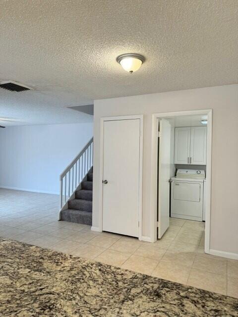 3822 38th Way, West Palm Beach, FL 33407 - stairway featuring washer and dryer, tile patterned floors, and a textured ceiling