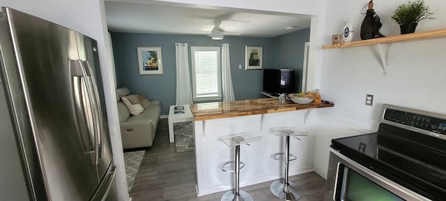 104 NE 5th St, Fort Lauderdale, FL 33301 - kitchen featuring appliances with stainless steel finishes, wood counters, dark wood-style flooring, a breakfast bar, and ceiling fan