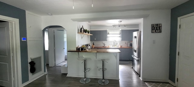 104 NE 5th St, Fort Lauderdale, FL 33301 - kitchen featuring wooden counters, open shelves, arched walkways, dark wood-style flooring, and freestanding refrigerator