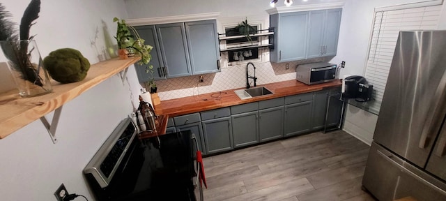 104 NE 5th St, Fort Lauderdale, FL 33301 - kitchen with appliances with stainless steel finishes, butcher block countertops, tasteful backsplash, light wood finished floors, and gray cabinetry