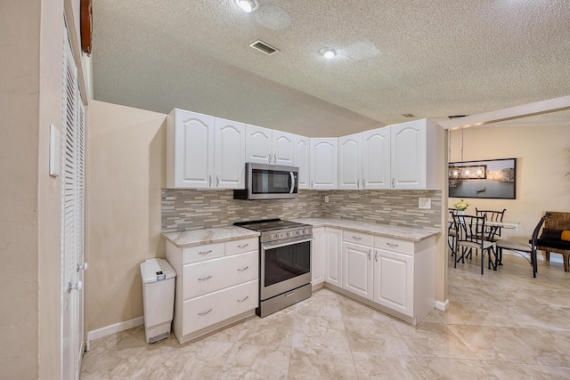 5330 NW 31st St, Margate, FL 33063 - kitchen featuring stainless steel appliances, tasteful backsplash, a textured ceiling, white cabinets, and vaulted ceiling
