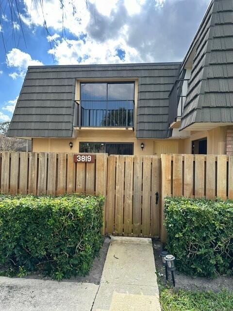 3819 38th Way, West Palm Beach, FL 33407 - view of exterior entry featuring mansard roof and stucco siding