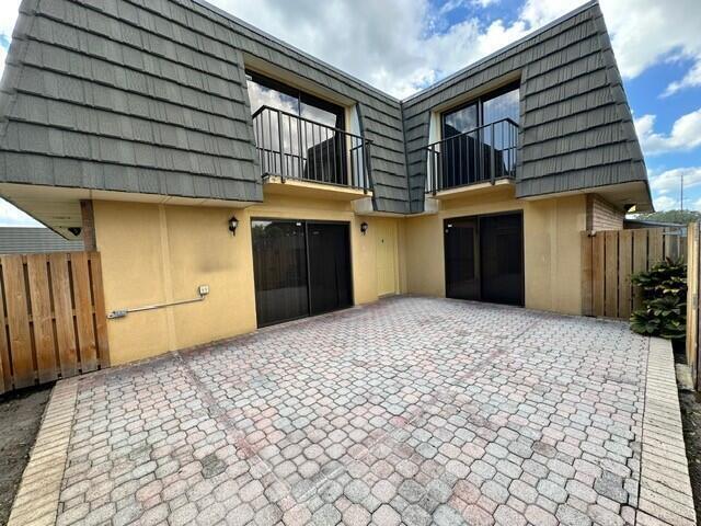3819 38th Way, West Palm Beach, FL 33407 - view of side of home featuring mansard roof, a balcony, stucco siding, a patio area, and driveway