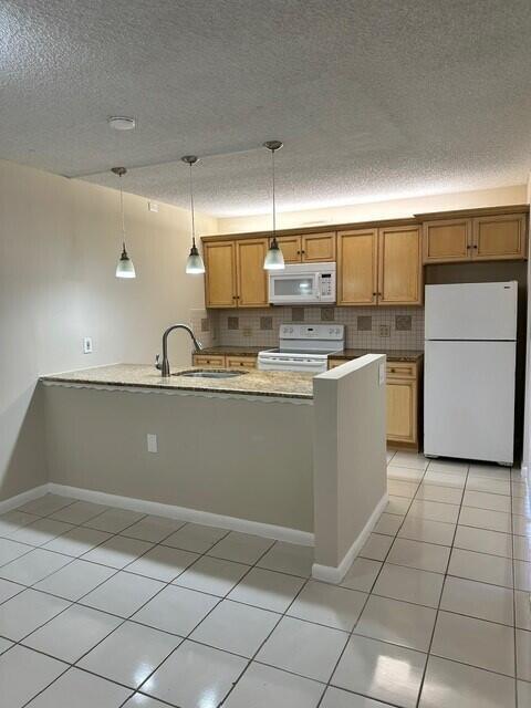3819 38th Way, West Palm Beach, FL 33407 - kitchen with white appliances, light tile patterned floors, a textured ceiling, decorative backsplash, and hanging light fixtures