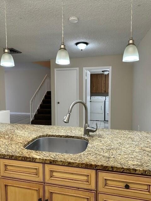 3819 38th Way, West Palm Beach, FL 33407 - kitchen featuring independent washer and dryer, light stone countertops, hanging light fixtures, and a textured ceiling