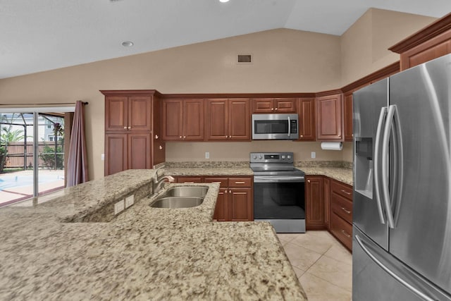 1070 SW Jennifer Ter, Port Saint Lucie, FL 34953 - kitchen featuring stainless steel appliances, light tile patterned floors, light stone counters, high vaulted ceiling, and brown cabinets